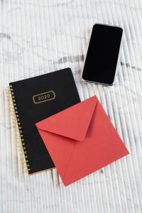 Red envelope, planner & Iphone on marble
