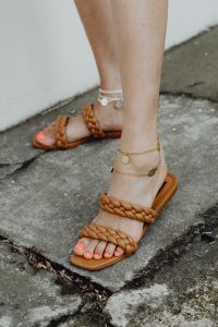 Feet in sandals with gold and silver jewelry