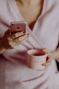 Kaboompics - A woman in a pink sweater holds a pink iPhone and a pink cup in her hands