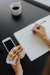 Kaboompics - A businesswoman eats a hamburger at work