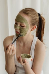 Kaboompics - Young Woman Applying Green Clay Mask to Her Face