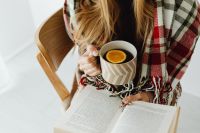 Kaboompics - A young girl holds tea and reads a book