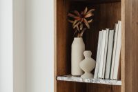 Kaboompics - Books on a bookcase - marble shelves - vase - dried flower