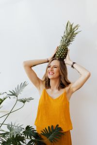 Kaboompics - A beautiful smiling young woman is holding a pineapple