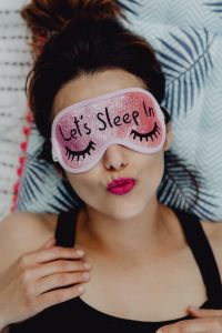 Kaboompics - Joyful girl relaxing in bedroom - top view of brunette women in pink sleeping mask