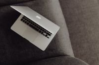 Close up view of closed laptop lying on grey armchair